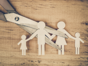 legal parenting agreement - image of scissors cutting paper cut out family in half on wooden table - call HCM Legal today