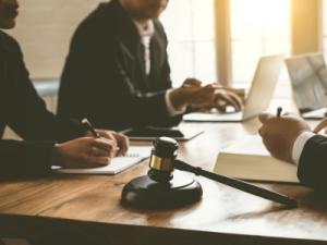separation and property settlement agreement - image of wooden gavel on a timber table with lawyer team and clients writing notes on paper and using laptops - call HCM Legal today