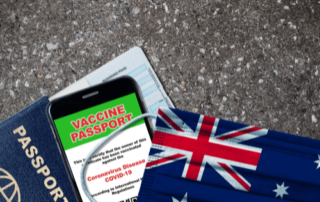 Australian flag, mobile phone with "Vaccine Passport" in red writing on green background with next to Australian Passport on bitumen - Applying for an Australian Visa for Canadians - contact HCM Legal